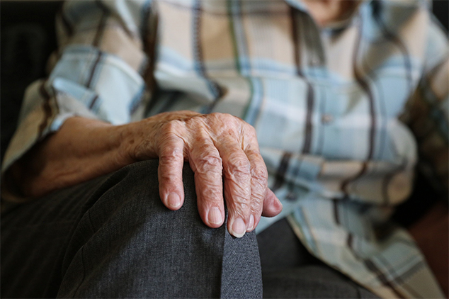 close up of an older persons hand on their own knee