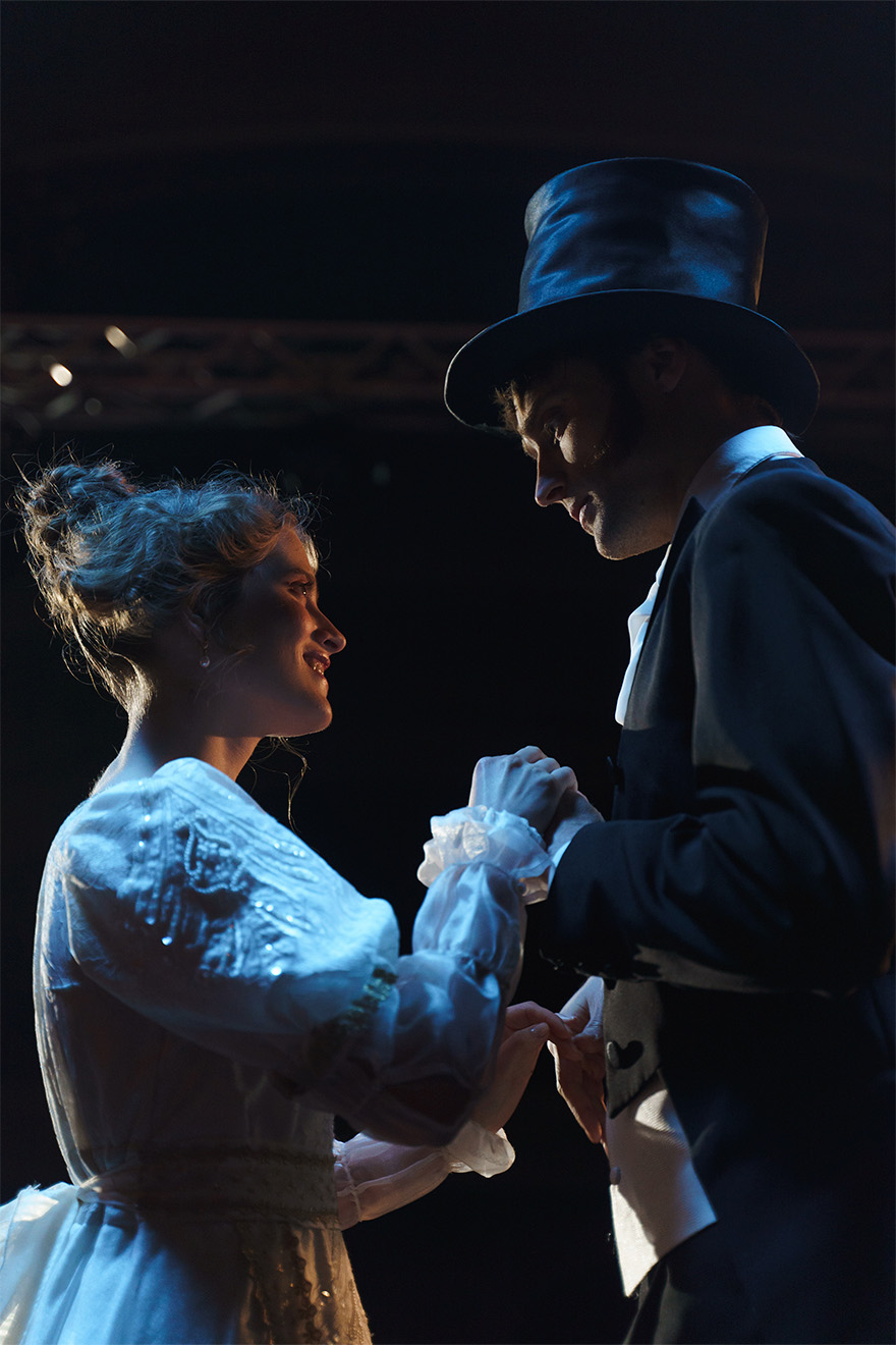 lady in dress and man in suit and top hat holding hands